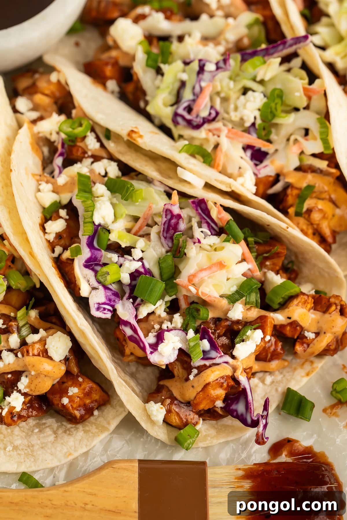 Smoky Chicken Taco Feast 3 Close-up of a single BBQ chicken taco, showing shredded chicken, coleslaw, and aioli.