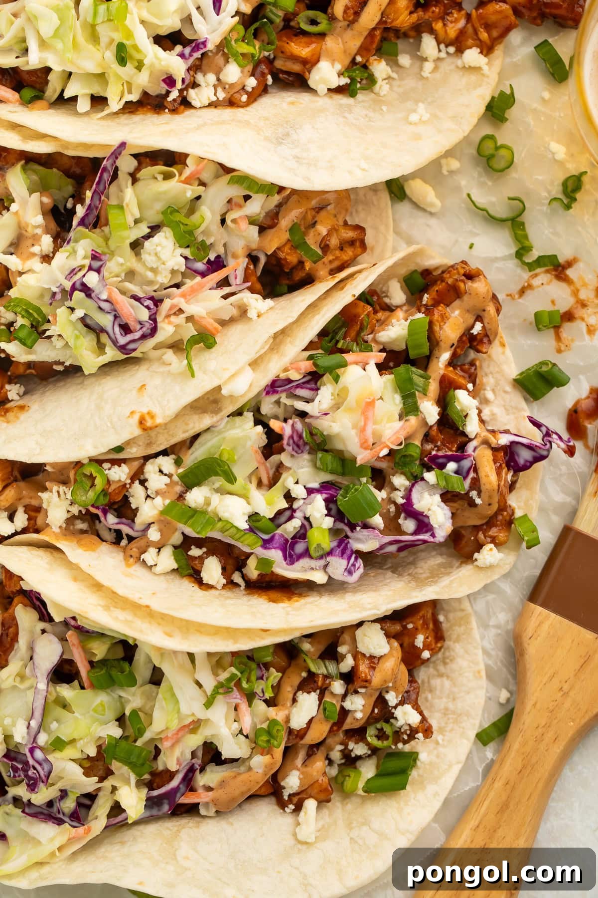 Smoky Chicken Taco Feast 4 Overhead view of several BBQ chicken tacos on a rustic platter with garnishes.