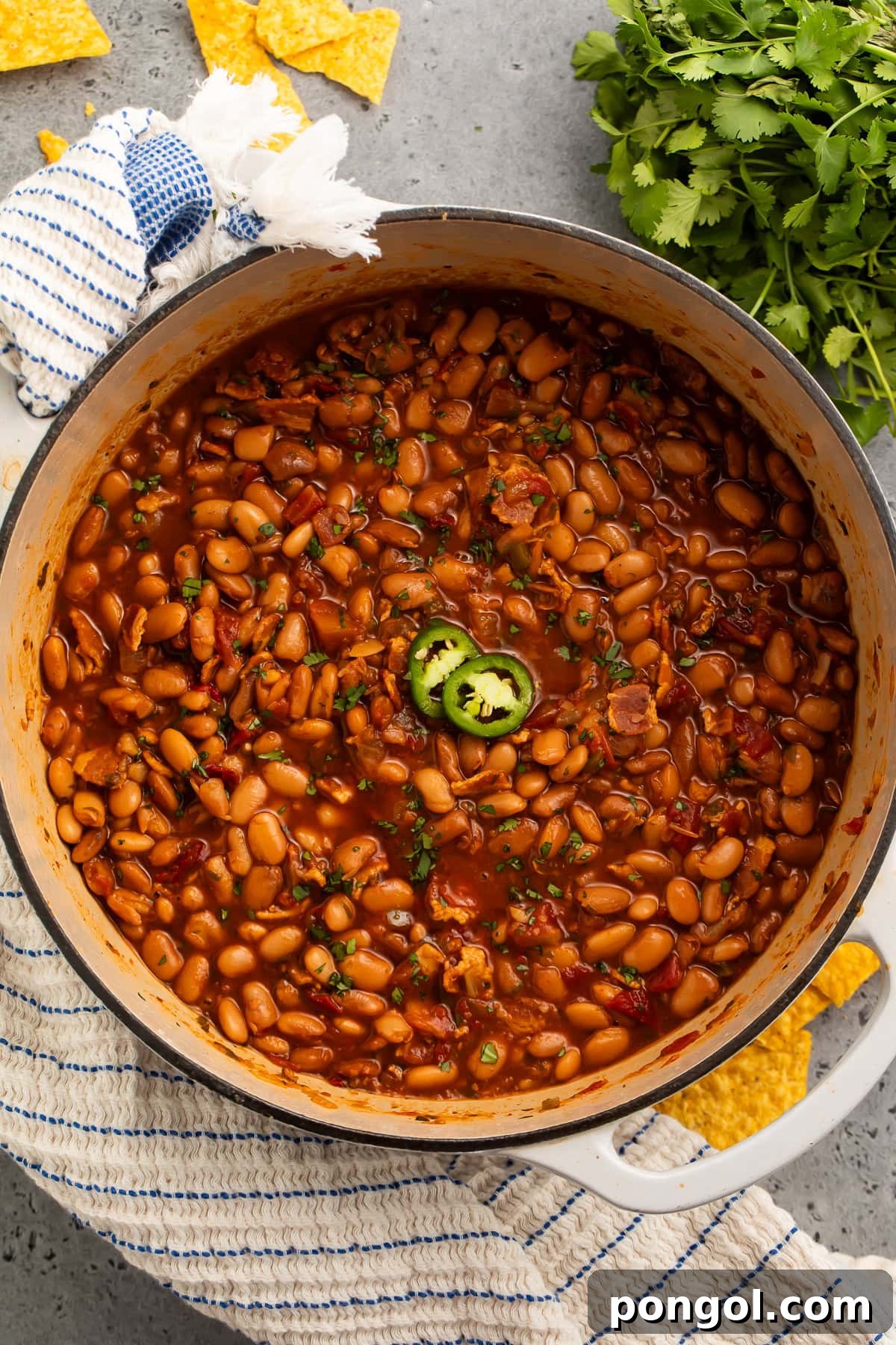 A close-up shot of charro beans in a rustic pot, showcasing the rich texture and vibrant ingredients.
