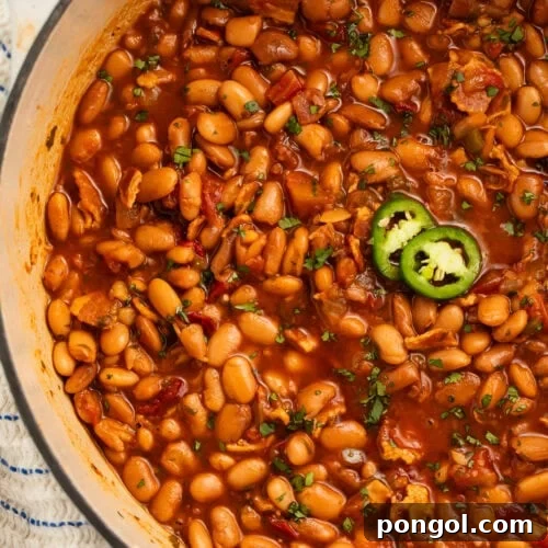 A large pot of charro beans topped with 2 jalapeño slices.