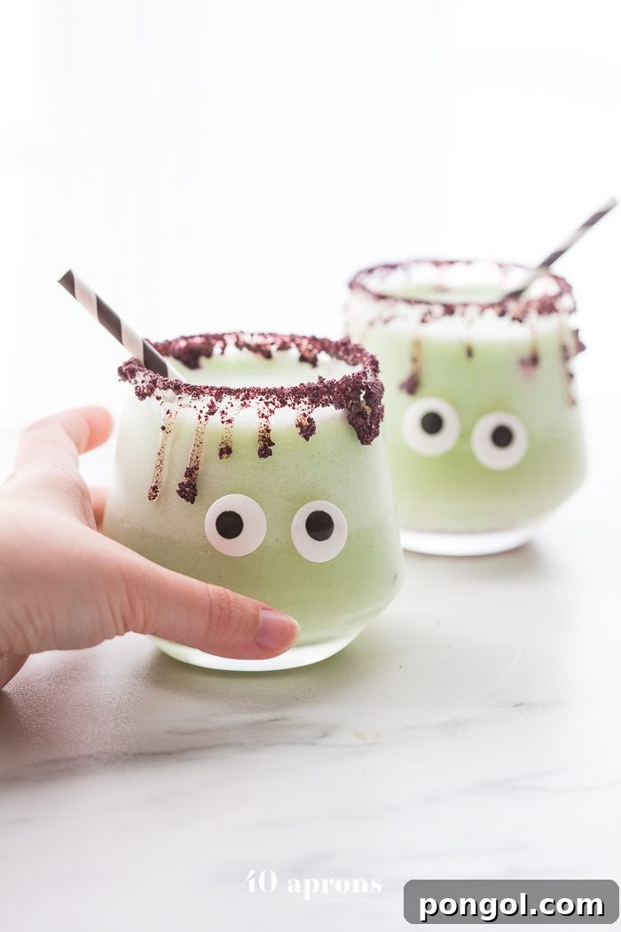 Monsteritas green Halloween cocktails with purple dripping rim and candy monster eyes in glasses