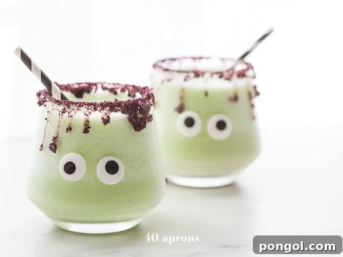 Monsteritas green Halloween cocktails with purple dripping rim and candy monster eyes in glasses with a black and white straw