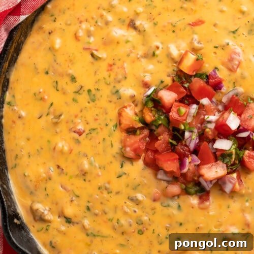 Creamy smoked queso dip with melted cheese and sausage in a cast iron skillet, garnished with fresh cilantro