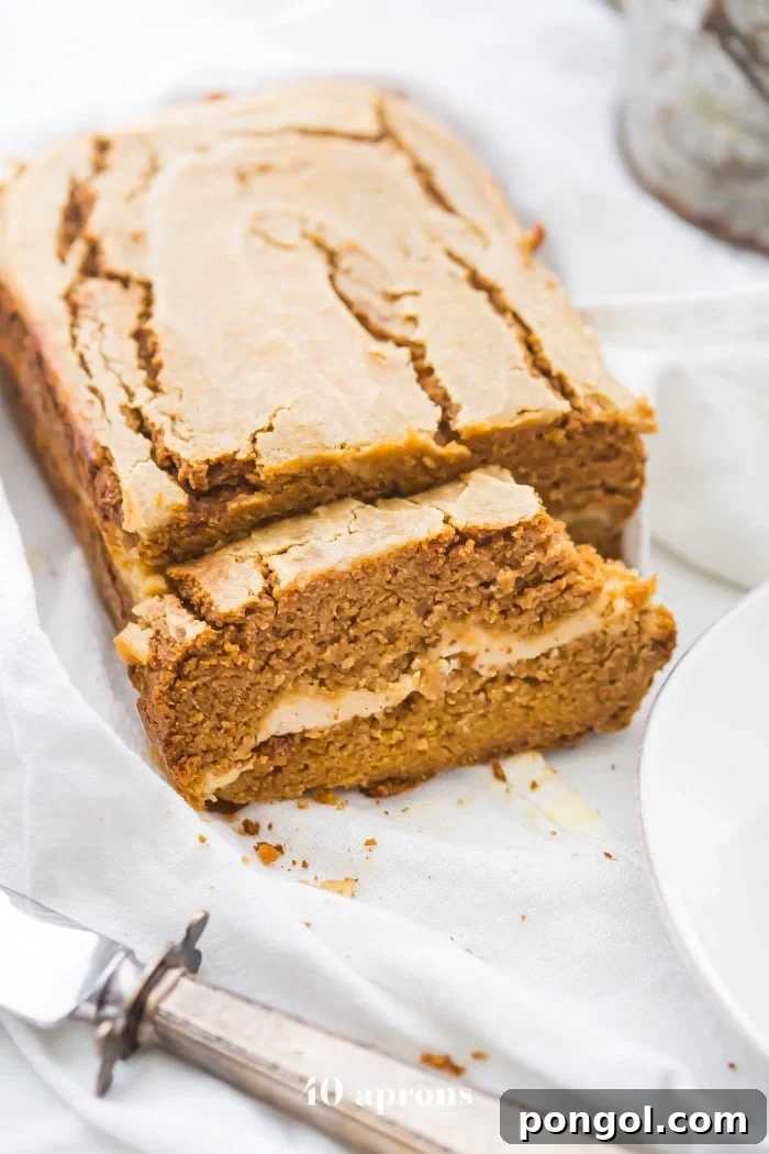 Paleo pumpkin bread with cream cheese swirl sliced with a bite out of one piece