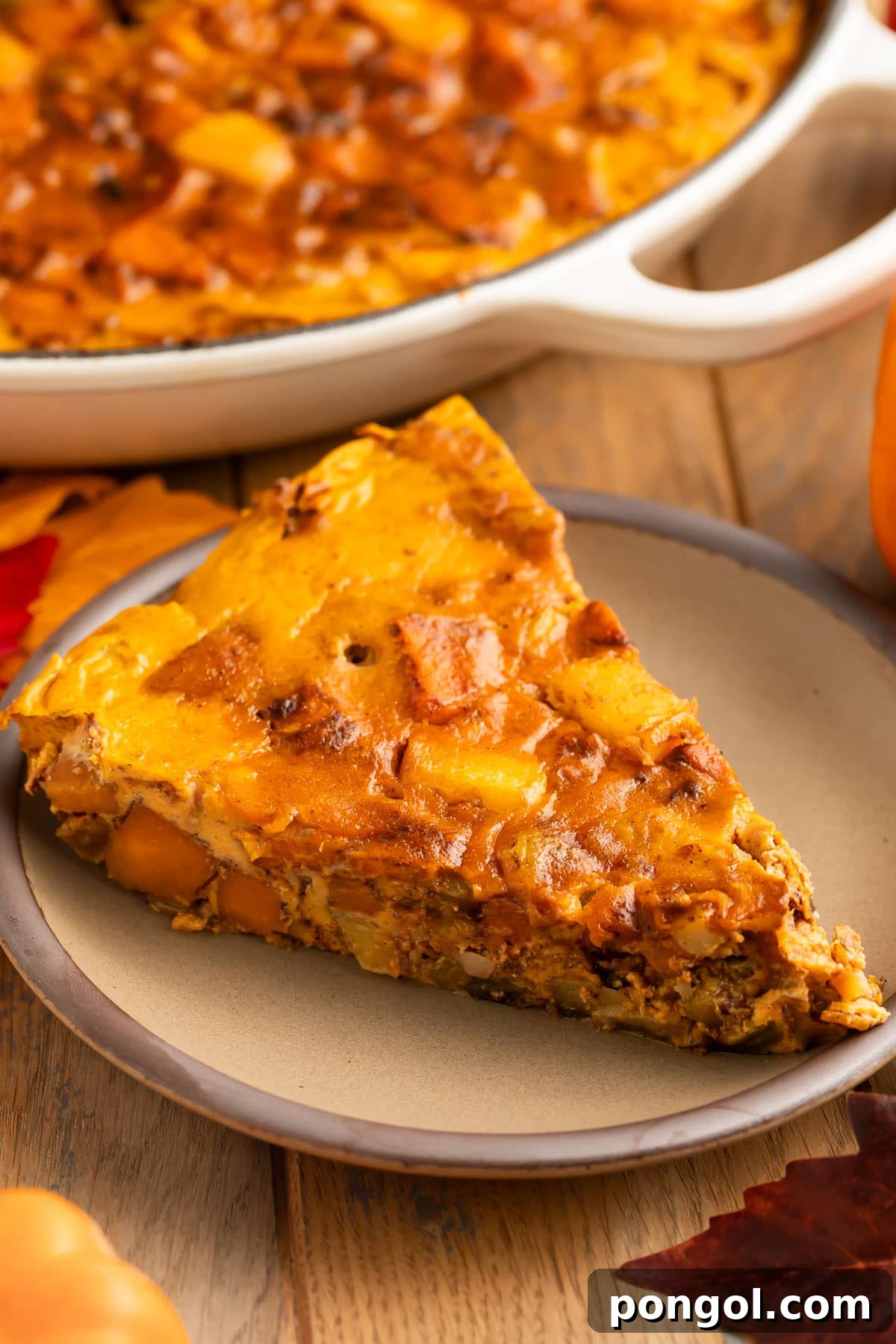 Warm Spiced Paleo Pumpkin Morning Bake 3 A triangular slice of a paleo pumpkin breakfast bake served on a small tan plate.
