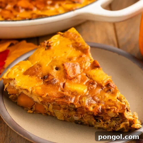 Warm Spiced Paleo Pumpkin Morning Bake 4 A triangular slice of a paleo pumpkin breakfast bake served on a small tan plate.