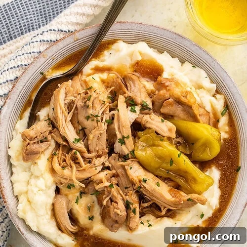 Mississippi chicken pot roast served over creamy mashed potatoes with rich gravy and pepperoncini peppers garnished with fresh parsley