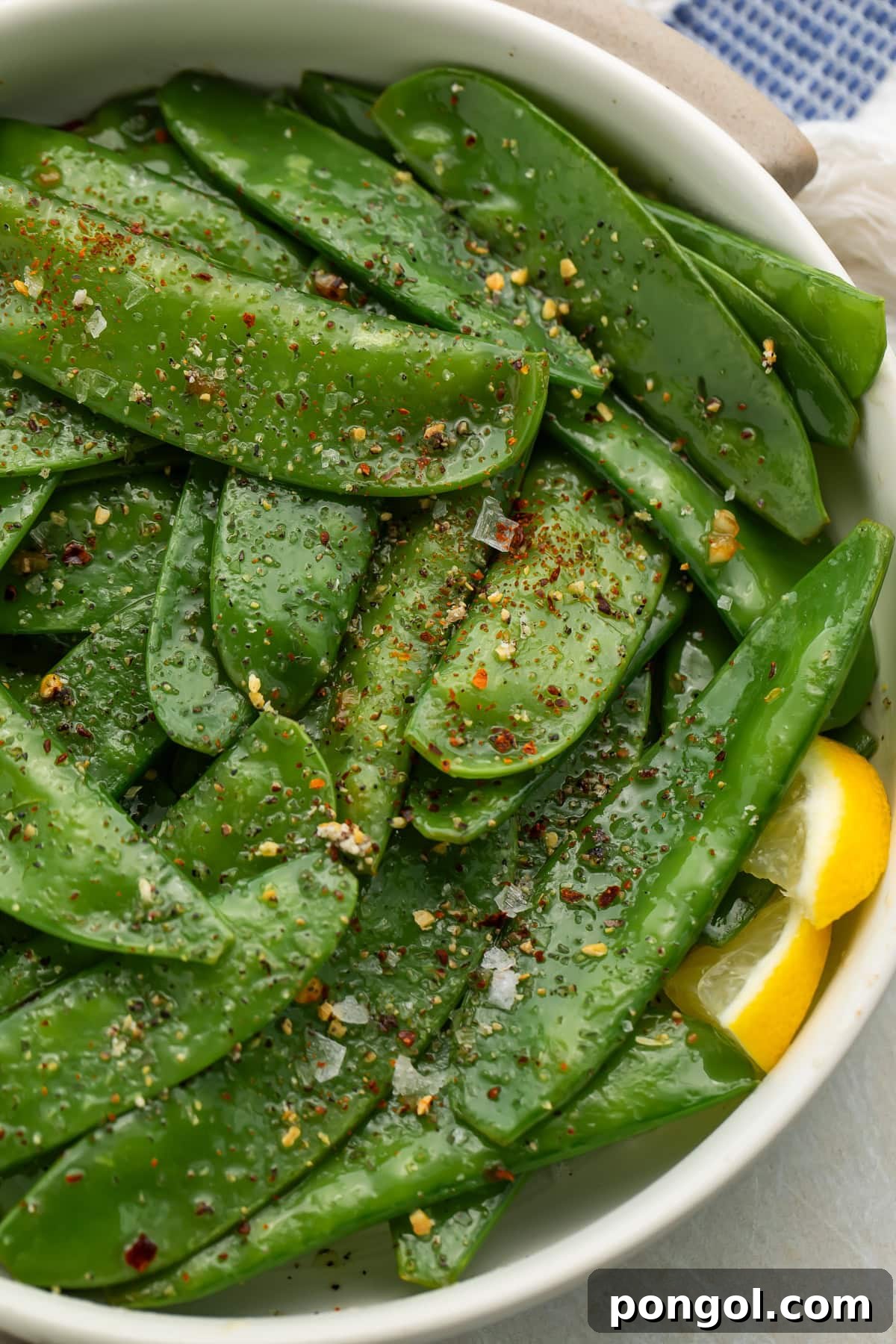 Overhead view of finished garlic butter snow peas with visible seasoning and herbs