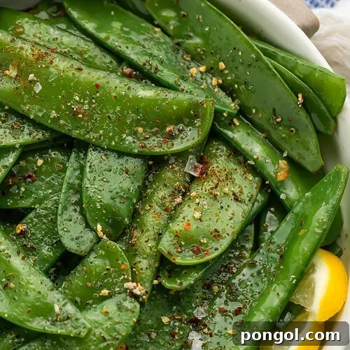 Overhead view of finished garlic butter snow peas with visible seasoning and herbs