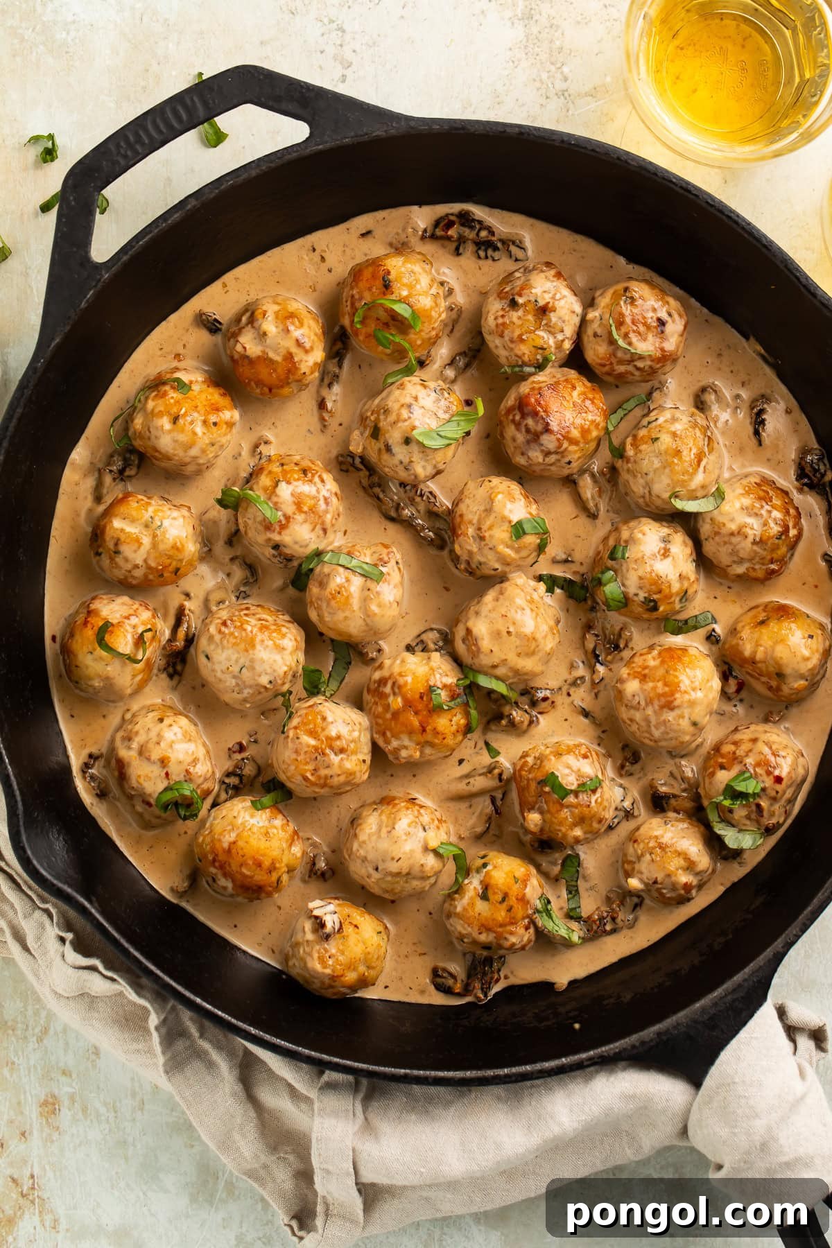 Golden brown chicken meatballs in creamy marry me sauce with sun-dried tomatoes in black cast iron skillet