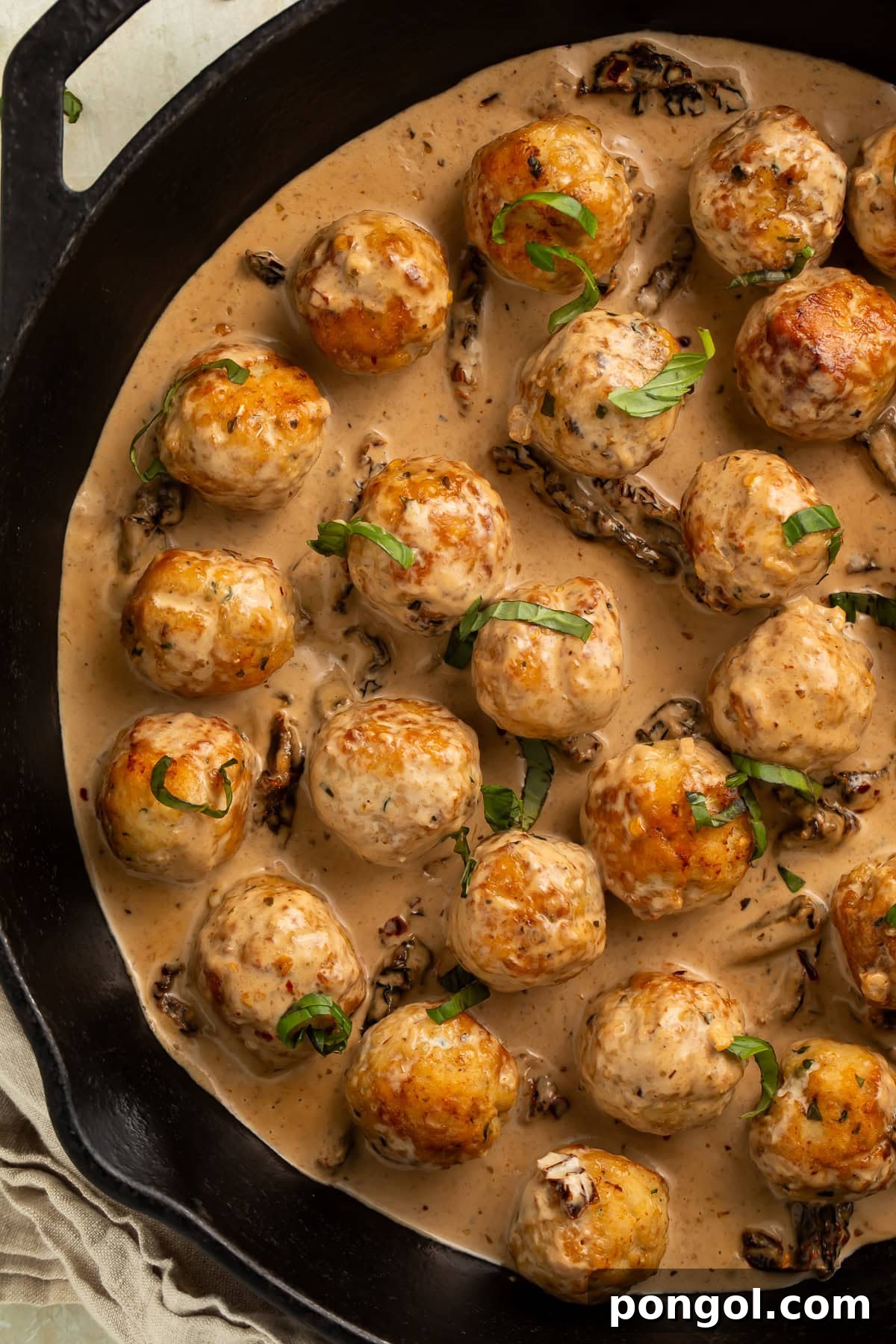 Overhead view of marry me chicken meatballs in cast iron skillet with creamy sun-dried tomato sauce