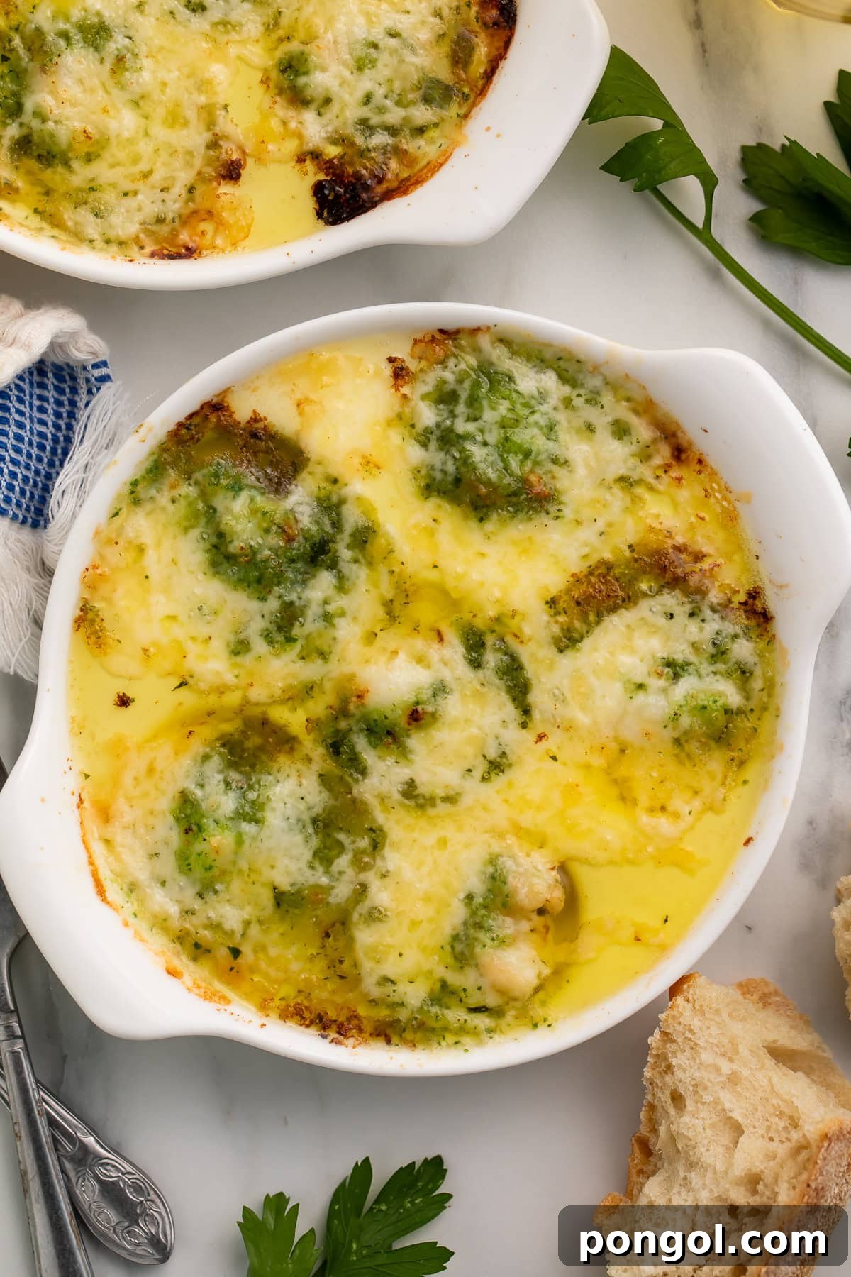 Close-up of lobster escargot in white ramekins with bubbling melted cheese and garnished with fresh parsley, ready to serve.
