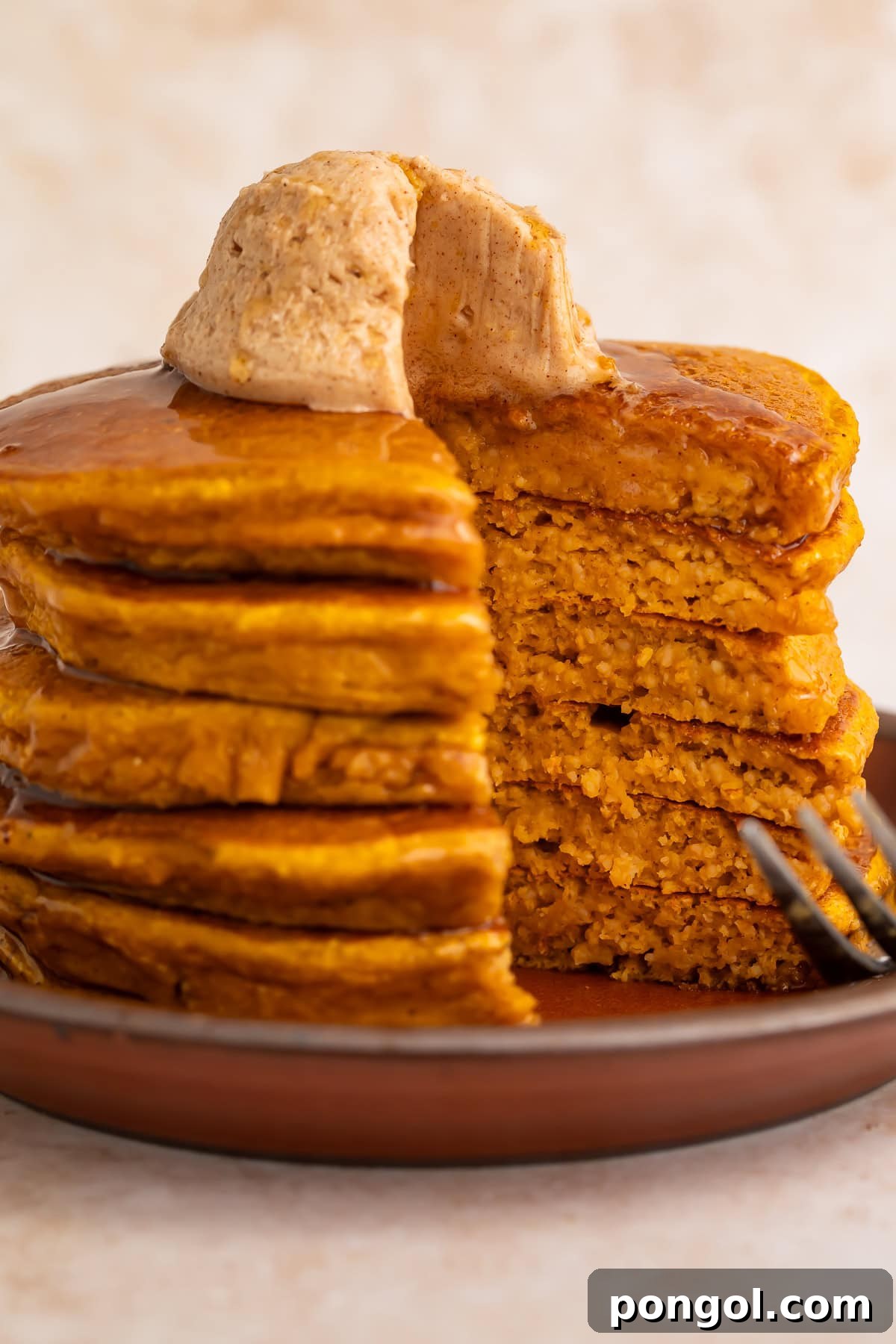 Cut pumpkin protein pancakes showing fluffy interior texture with cinnamon butter and fork