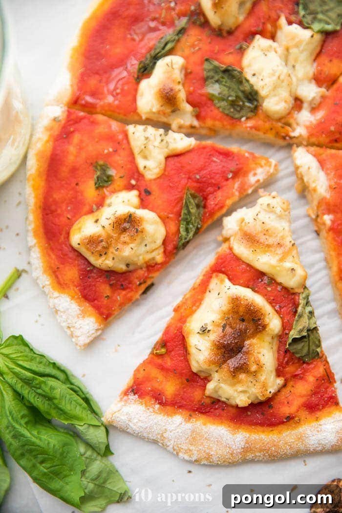 A whole paleo pizza recipe with a slice cut out, showcasing a perfect crust and dairy-free mozzarella