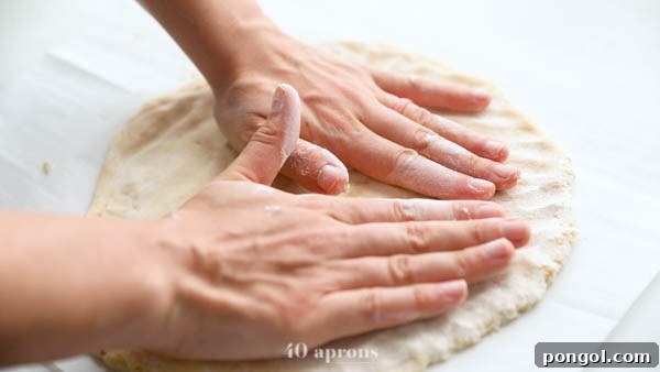 Patting out half of the paleo pizza dough onto parchment paper