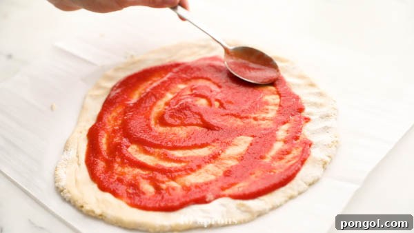 Spreading tomato sauce onto a paleo pizza crust