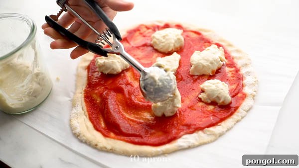 Using a disher to place dairy-free cheese on paleo pizza crust