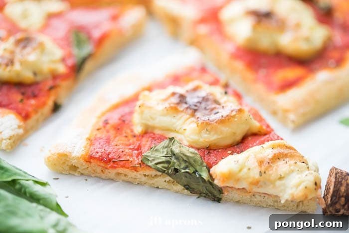 A close-up of a slice of paleo pizza, highlighting its airy and chewy cassava flour crust