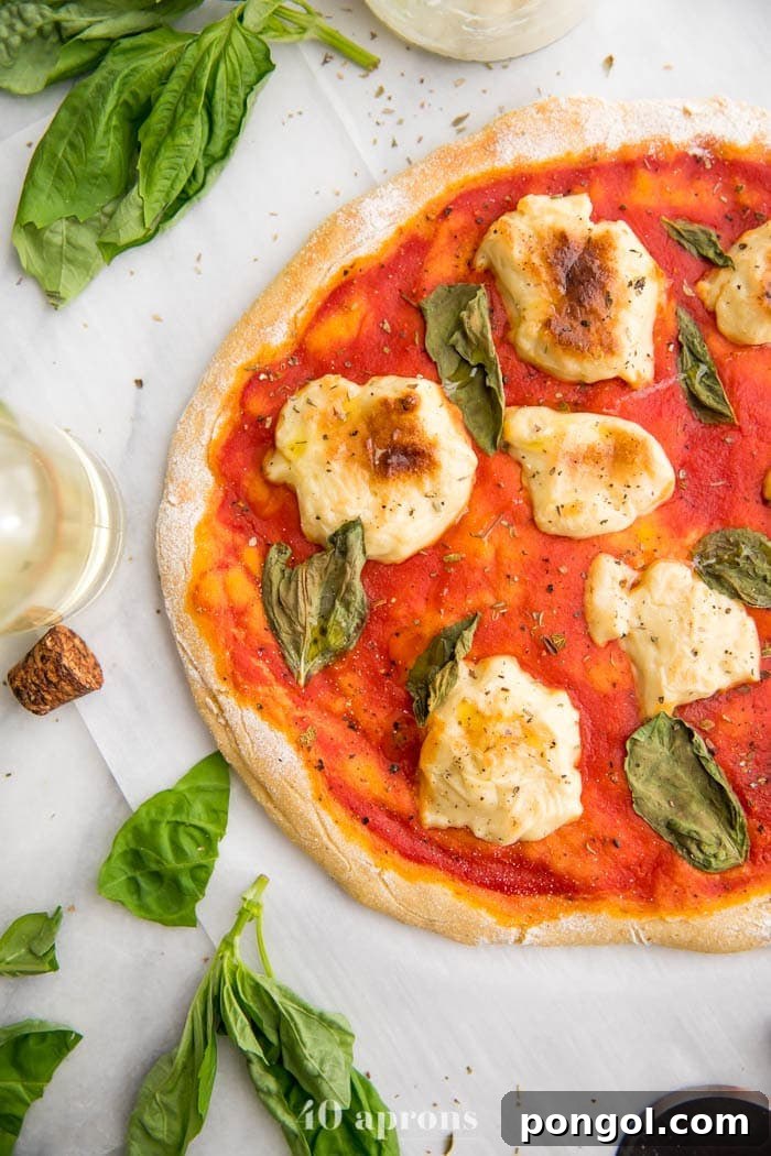 A slice of paleo pizza with an airy and chewy crust, topped with fresh basil and dairy-free mozzarella