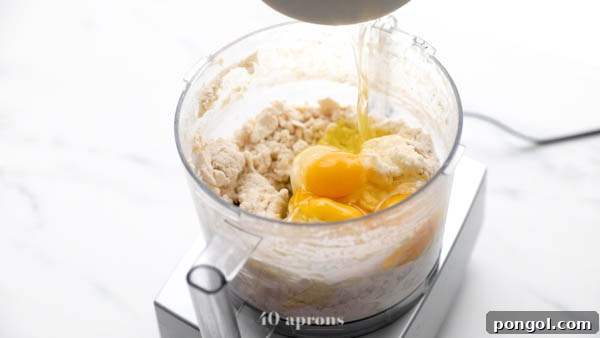 Combining flours, olive oil, salt, yeast mixture, and eggs in a food processor for paleo pizza dough