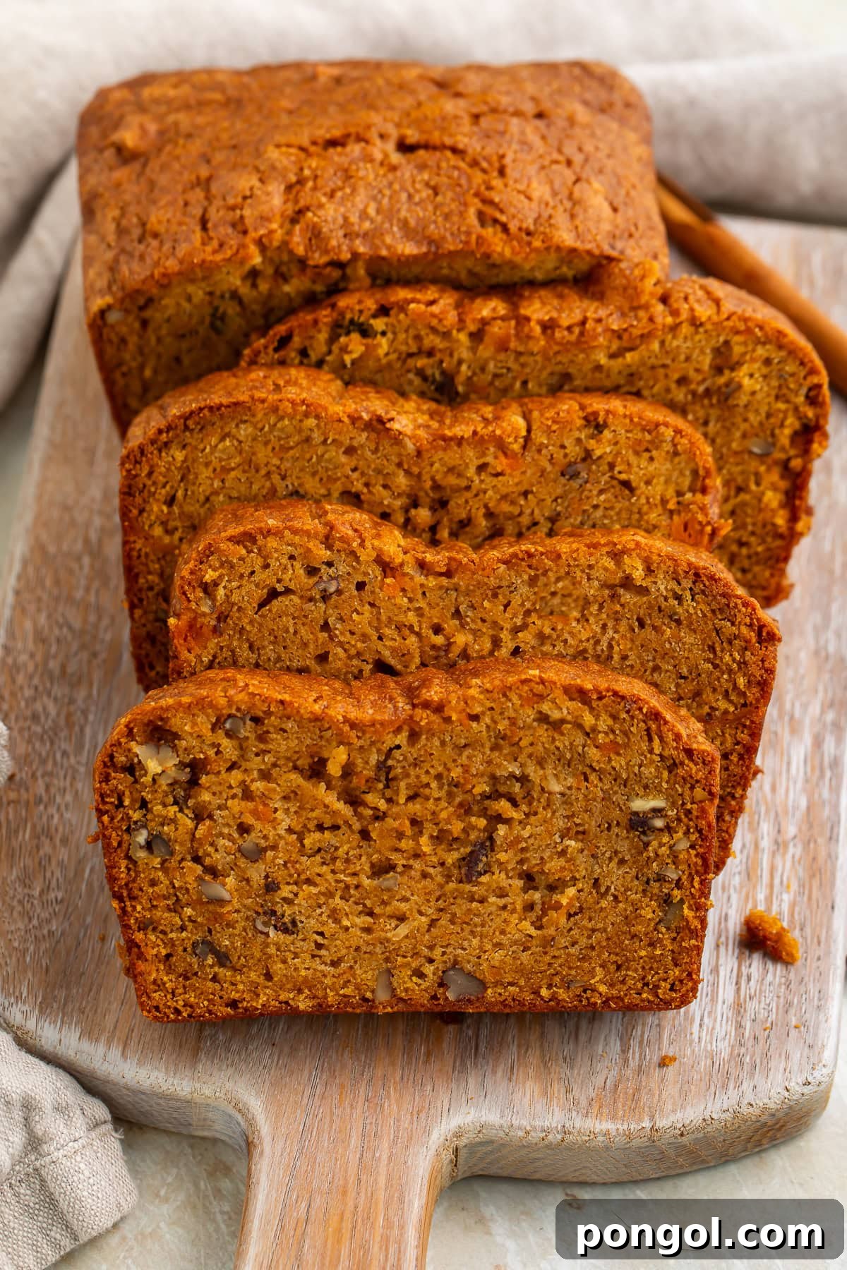 Sweet potato bread loaf partially sliced on cutting board with visible nuts and crumb texture
