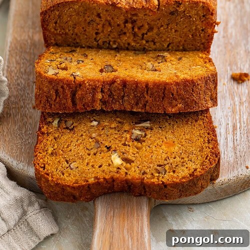 Sliced sweet potato bread with pecans on wooden cutting board showing moist orange crumb