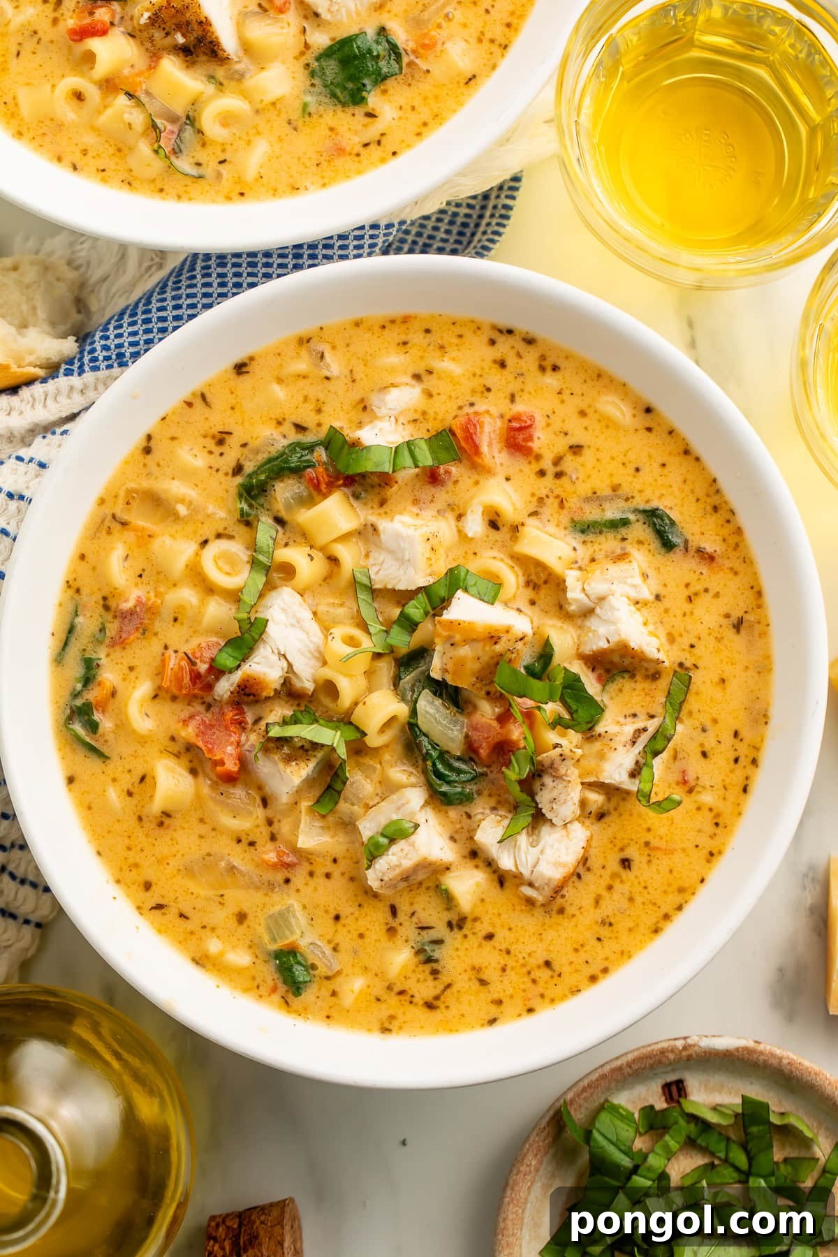Love-Struck Chicken Soup 2 Marry Me Chicken Soup in white bowls with ditalini pasta, chunks of chicken, sun-dried tomatoes, and fresh basil garnish, served with white wine