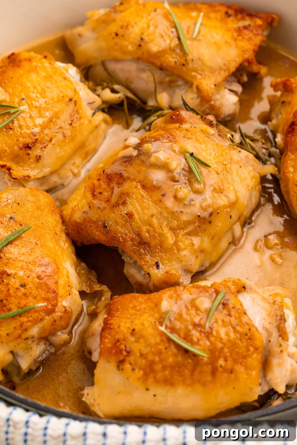 Sticky Maple Dijon Chicken Thighs 2 Crispy golden maple dijon chicken thighs in a white ceramic skillet, garnished with fresh rosemary.