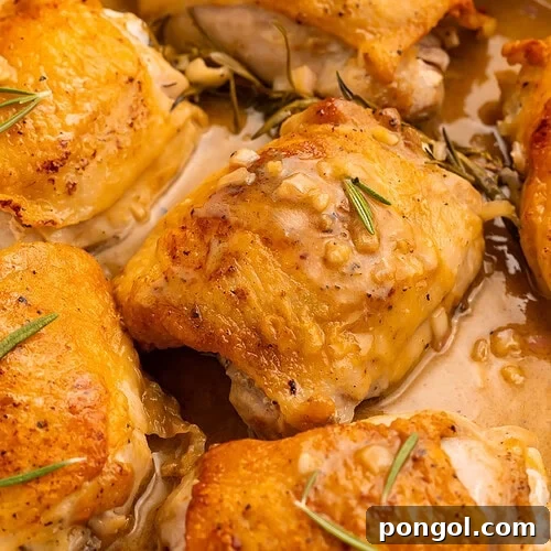 Maple dijon chicken thighs with crispy golden skin in white ceramic skillet, ready to serve.
