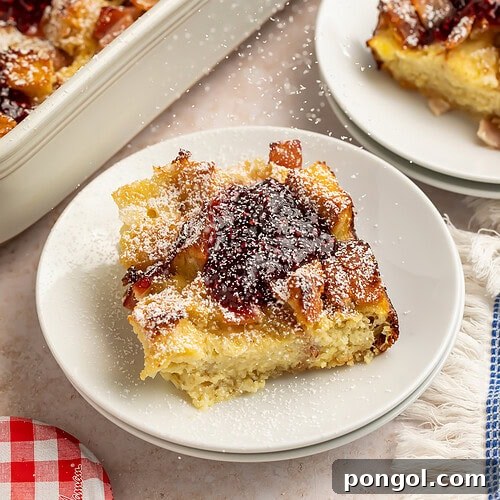 Monte Cristo casserole slices on white plates with raspberry jam and powdered sugar.