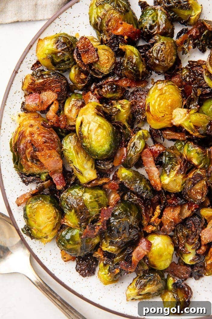 Dark trimmed white plate full of roasted brussels sprouts and bacon