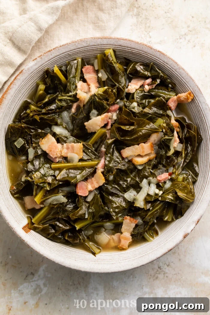 Overhead view of a white bowl of Instant Pot collard greens with bacon on a neutral tabletop.