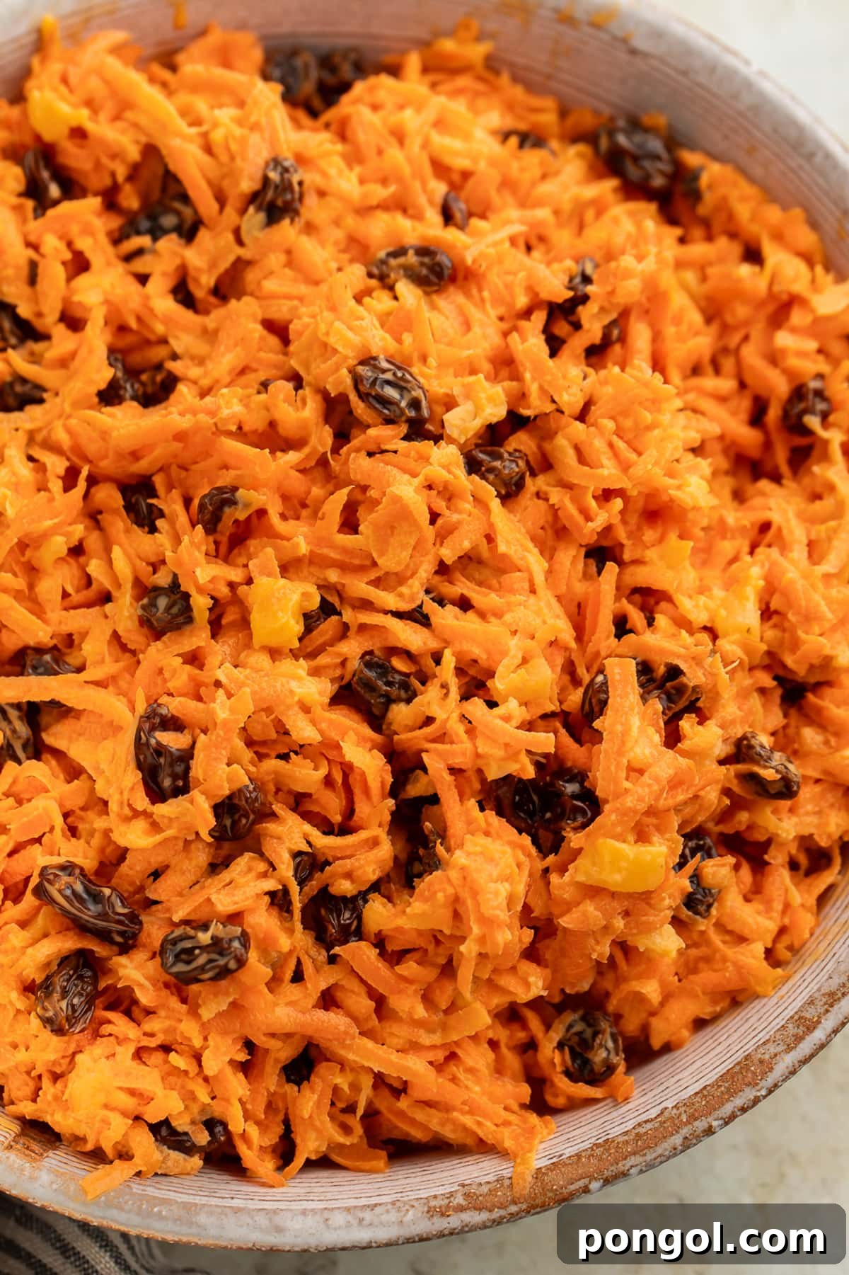 Close-up of a large bowl of carrot raisin salad.