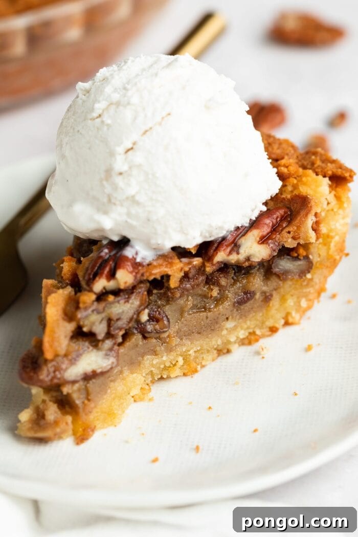 slice of keto pecan pie on a plate with sugar-free vanilla ice cream on top