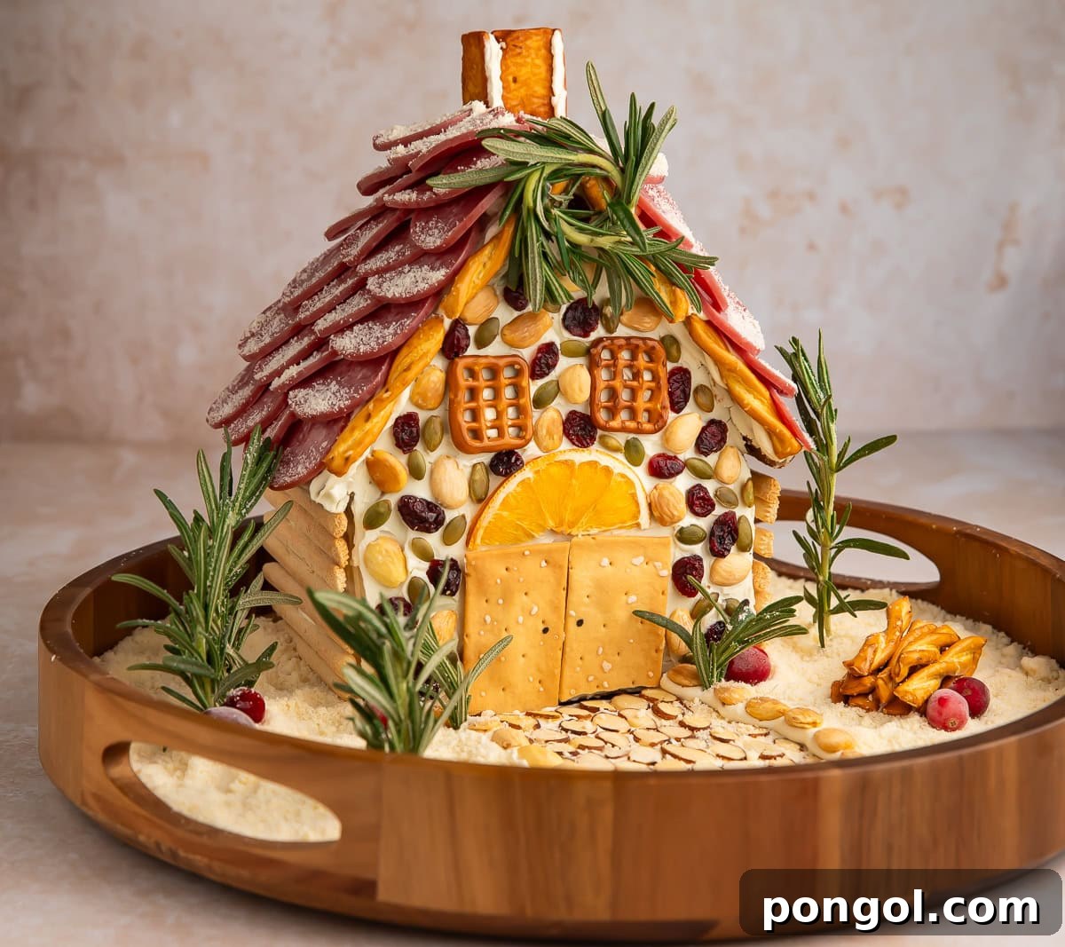 Full view of Christmas charcuterie chalet on wooden lazy Susan with salami roof and festive decorations.
