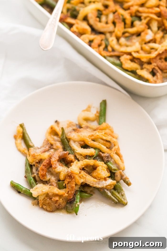 A close-up of a serving of Whole30 green bean casserole, showing the creamy texture and crispy onion topping. The dish is paleo, grain-free, and dairy-free, making it a healthy Thanksgiving option.
