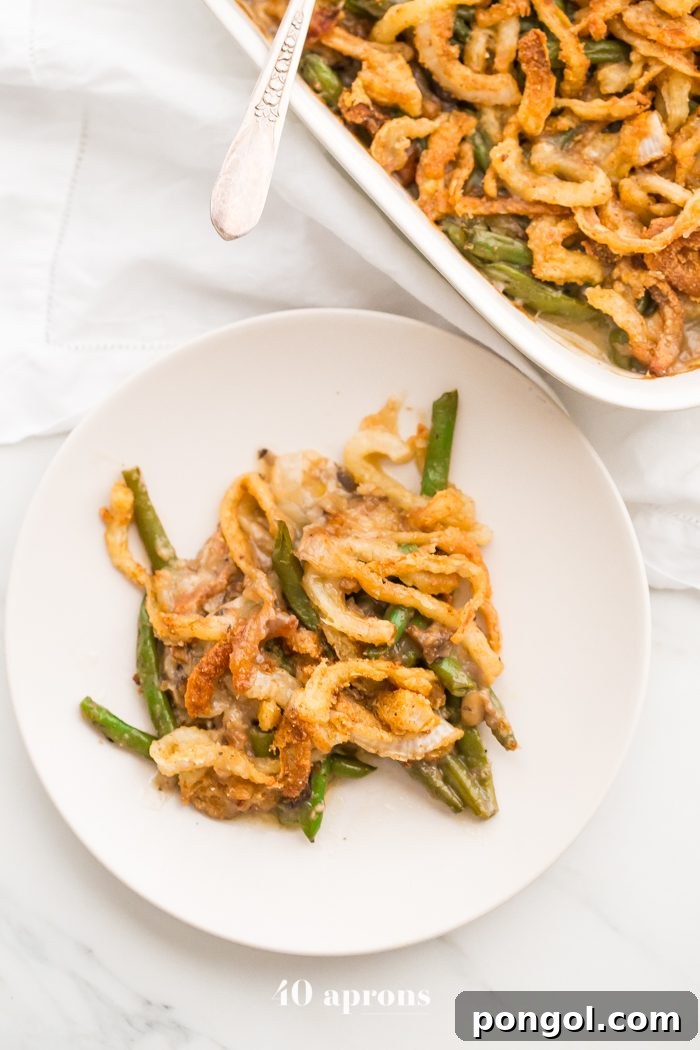 A full view of the baked Whole30 green bean casserole in a rustic baking dish, ready for serving at a Thanksgiving meal. This grain-free and dairy-free recipe is a testament to healthy and delicious holiday eating.