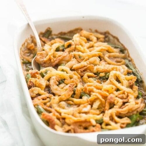 A detailed close-up of the Whole30 Green Bean Casserole, showcasing its creamy interior and crispy onion topping. This paleo, grain-free, and dairy-free dish is a healthy Thanksgiving staple.