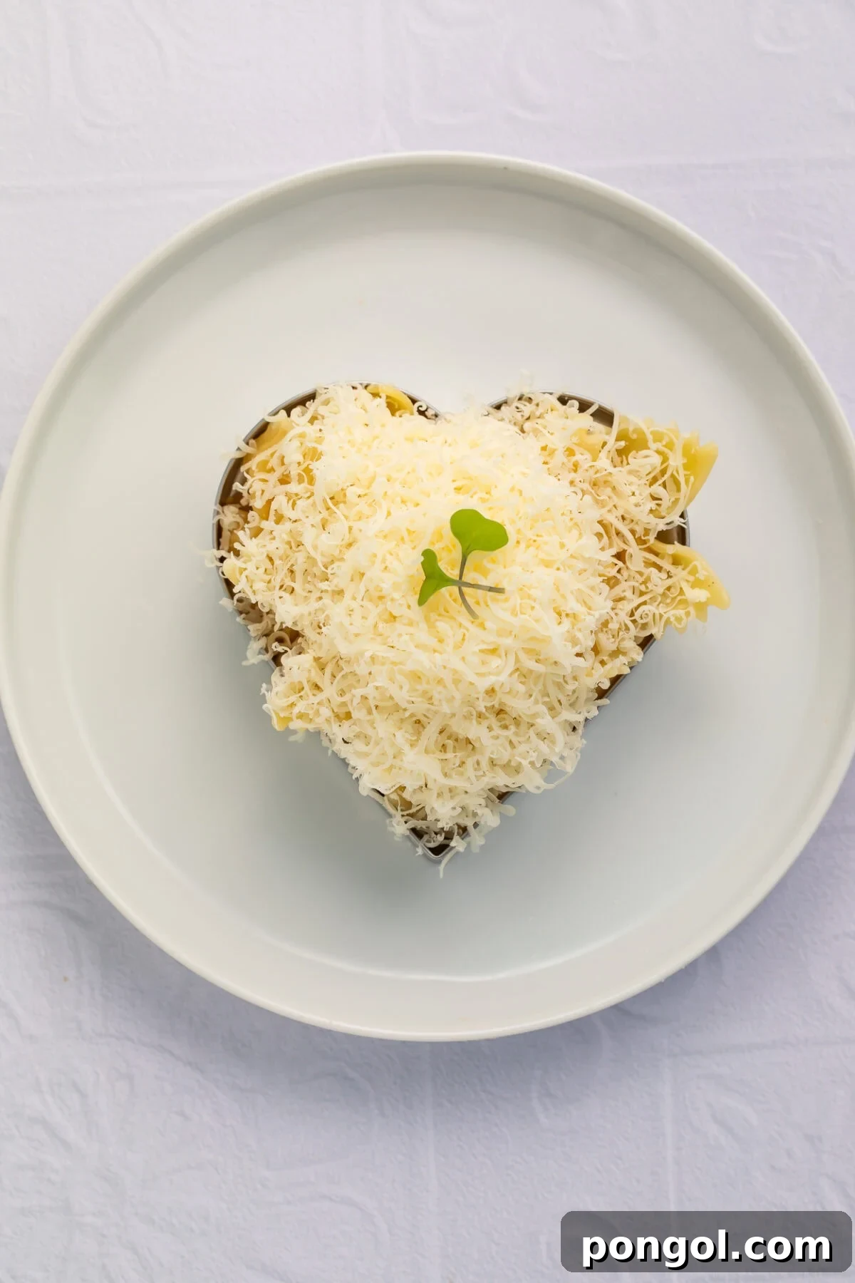 Heart-shaped buttered farfalle pasta with Parmesan snow, plated elegantly for a kids' Valentine's dinner