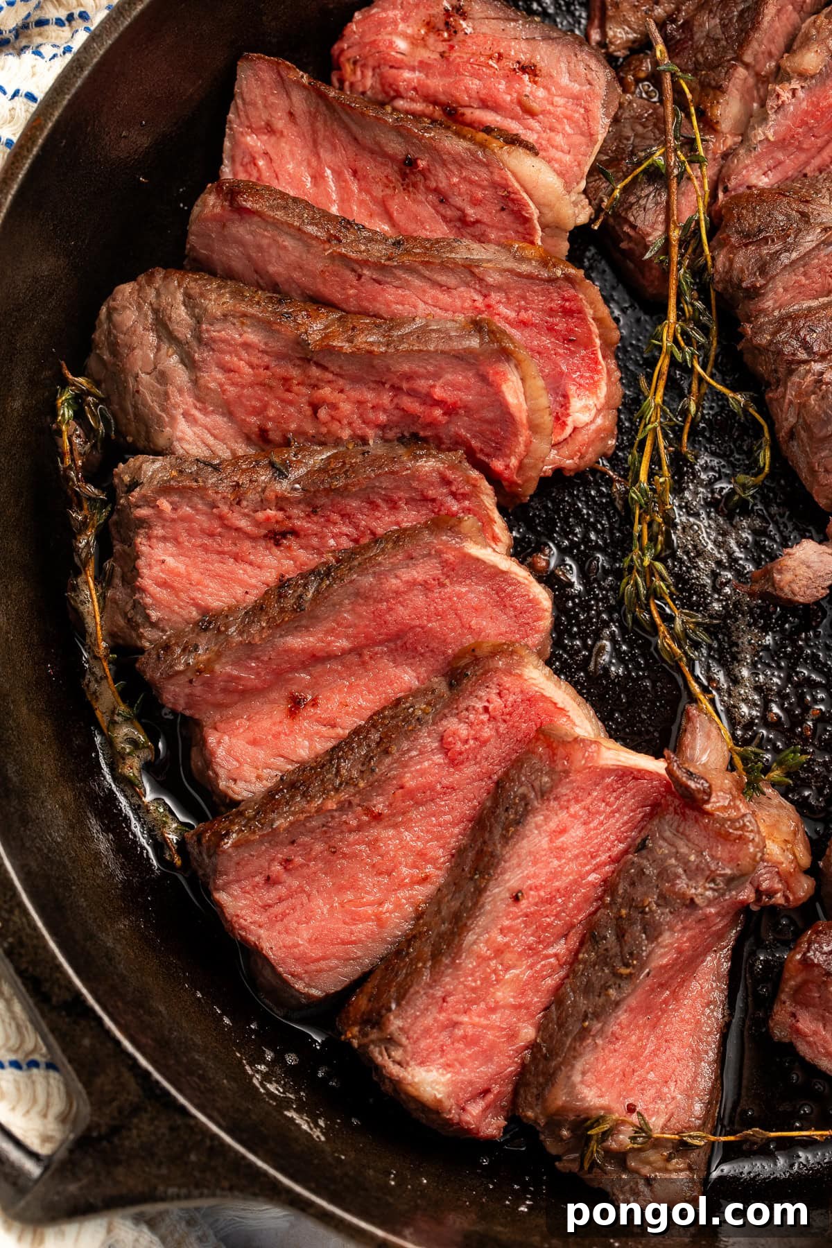 Perfectly cooked medium-rare steak slices nestled in a cast iron skillet, garnished with fresh thyme and garlic, showcasing ideal pink doneness for a romantic dinner