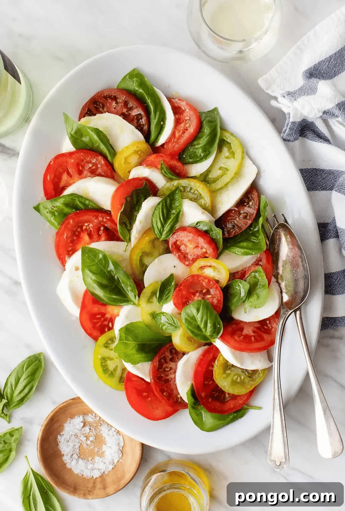 Classic Caprese salad featuring soft, creamy fresh mozzarella, ripe juicy tomatoes, and vibrant green basil leaves, drizzled with olive oil