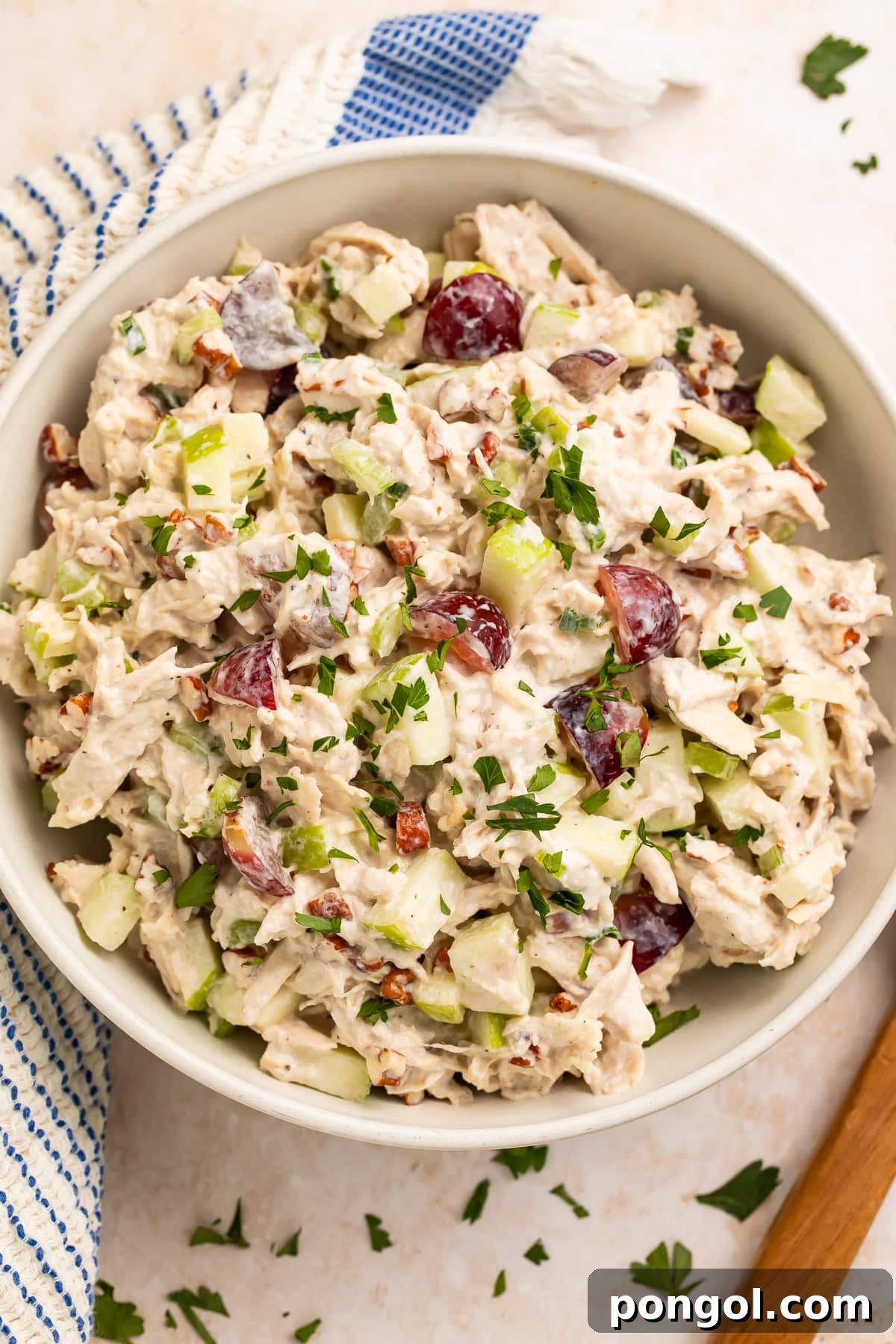 Wholesome Protein-Packed Chicken Salad 3 High protein chicken salad in white bowl on wooden surface with blue striped kitchen towel and fresh parsley