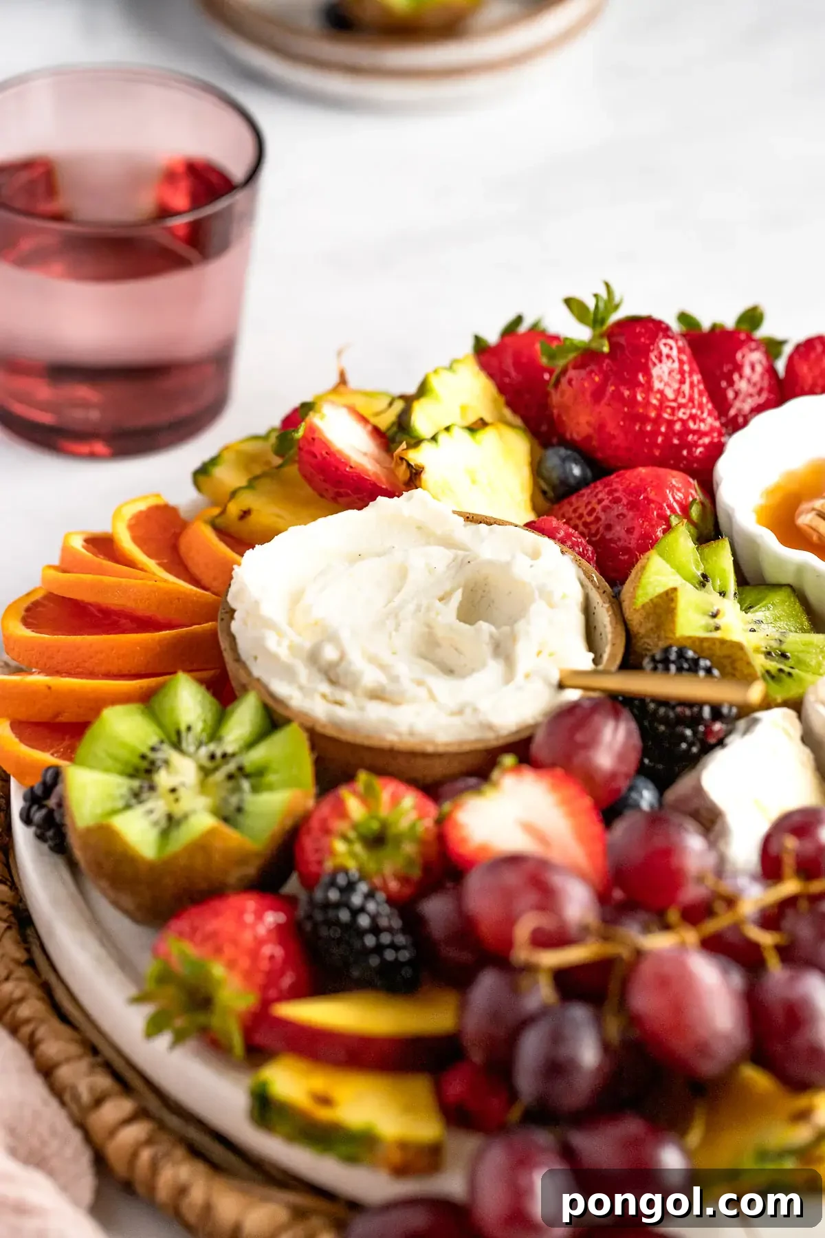 A refreshing fruit charcuterie board with sliced oranges, a variety of grapes, and berries, presented on a round wooden board.