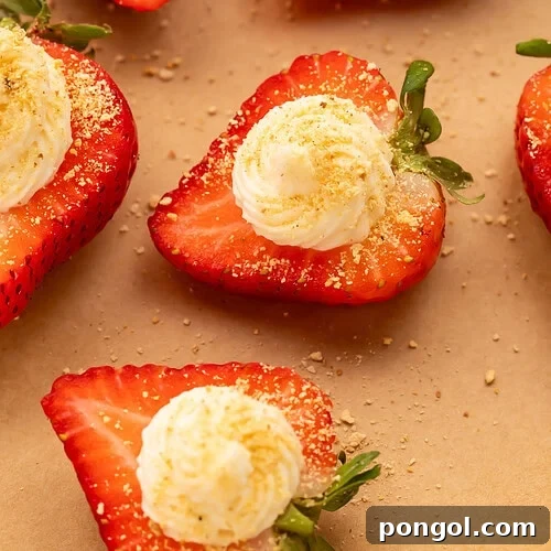 Close-up of deviled strawberries with piped cream cheese filling and graham cracker crumbs on parchment paper