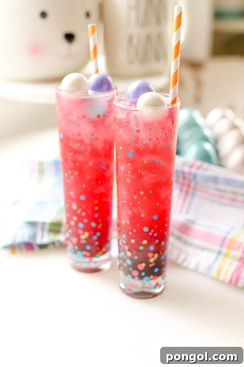 Easter Feasts Gifts and Fun Your Complete Celebration Guide 14 Two tall glasses of pink Easter mocktail adorned with pastel candy eggs and orange striped straws, resting on a colorful plaid napkin, perfect for a refreshing kid-friendly drink.