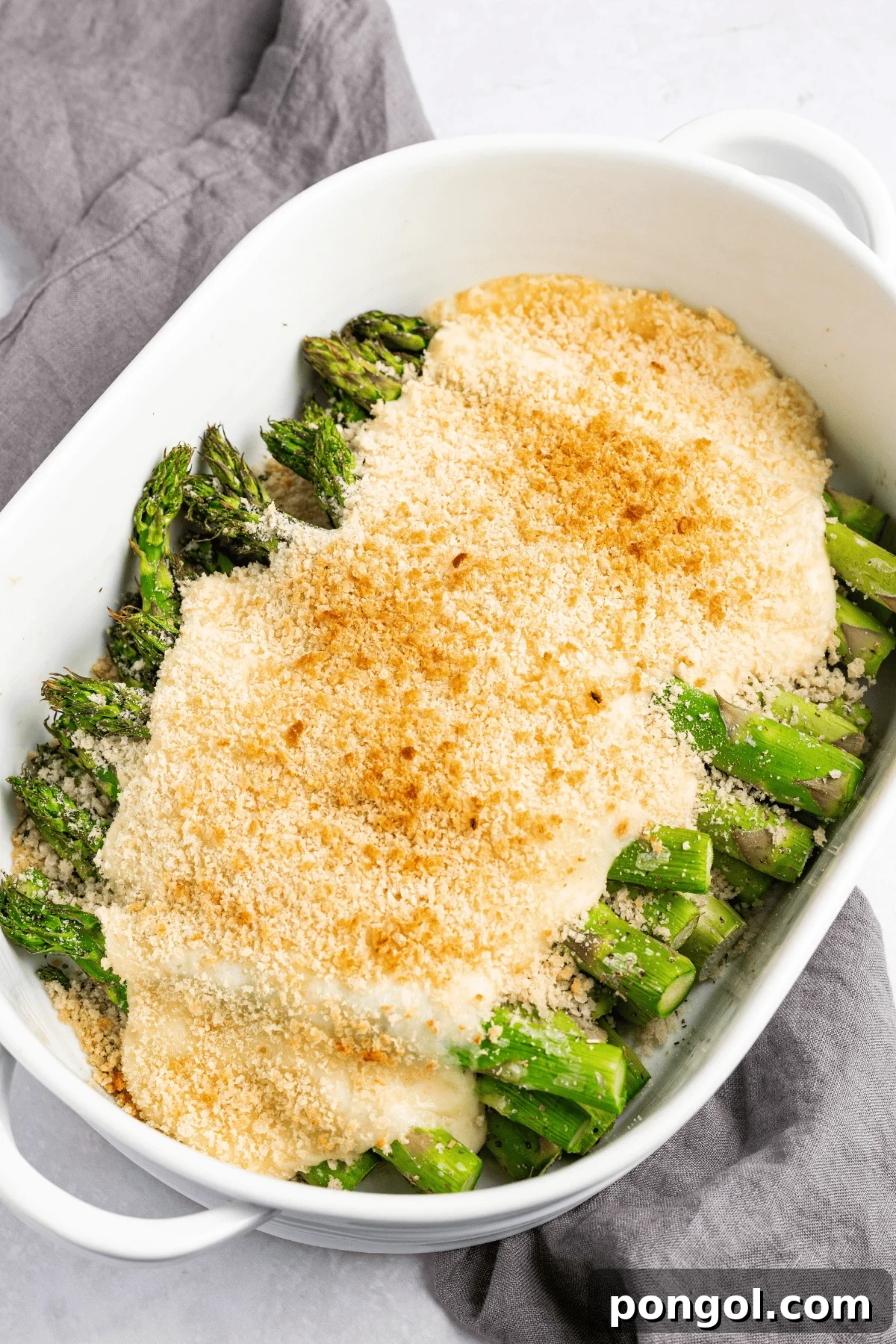Easter Feasts Gifts and Fun Your Complete Celebration Guide 4 Overhead view of cheesy asparagus casserole in a white oval baking dish with golden crumb topping, perfect for an Easter side dish.