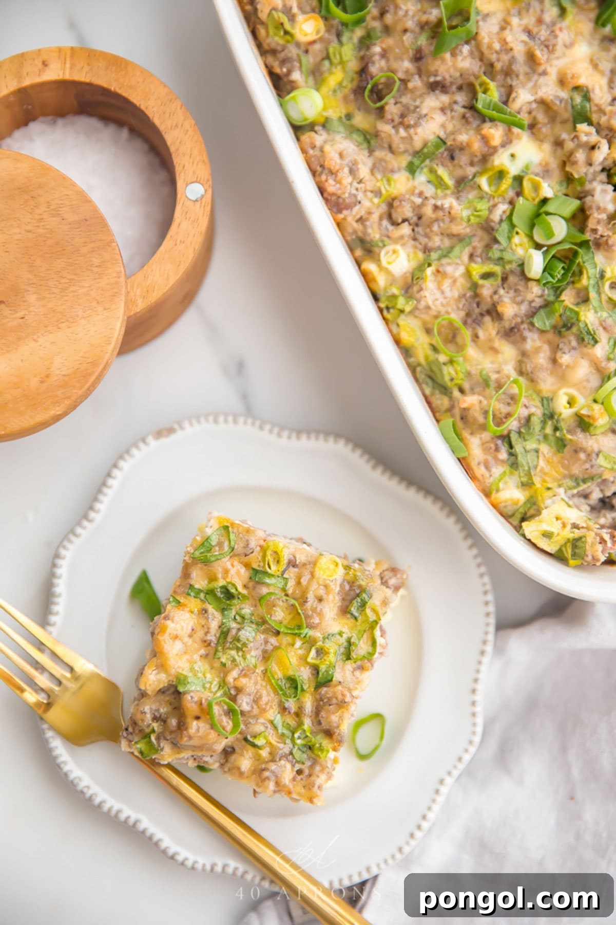 Top down view of a square of a Whole30 hashbrown casserole on a plate next to a casserole dish.