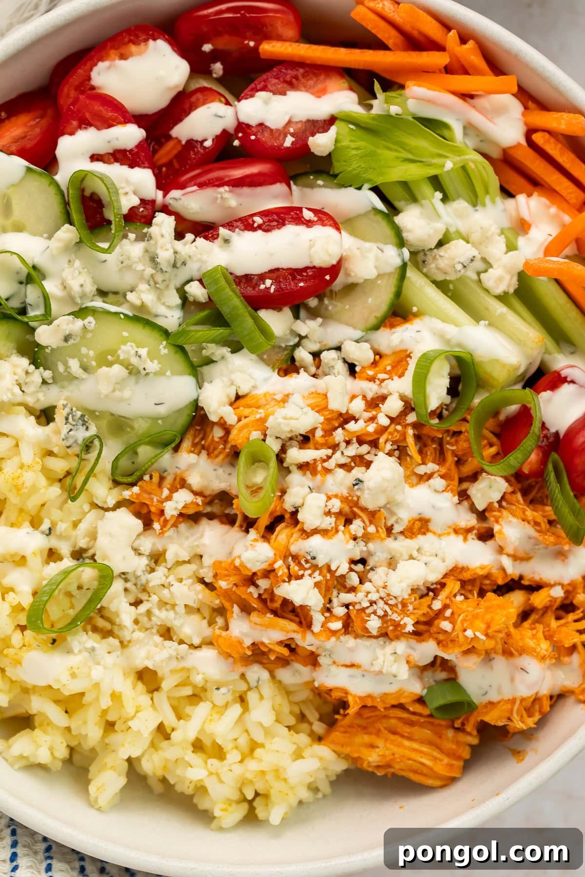 buffalo chicken bowls with shredded chicken, rice, fresh vegetables, and blue cheese crumbles in white bowls