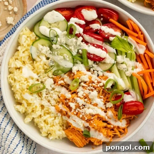 buffalo chicken bowls with shredded chicken, rice, fresh vegetables, and blue cheese crumbles in white bowls