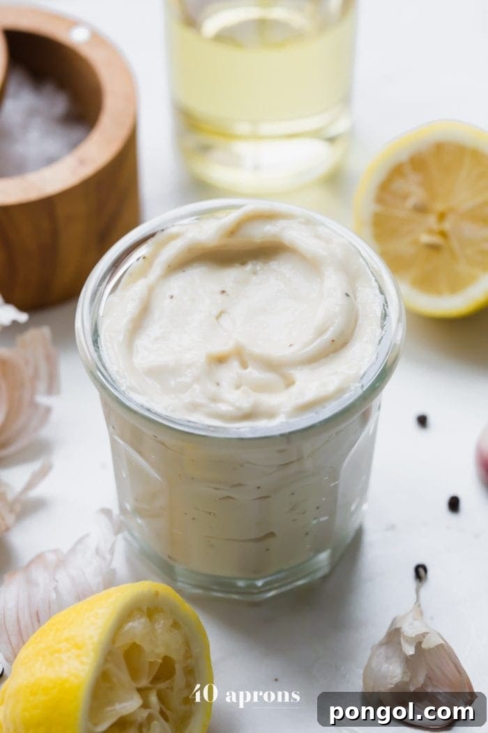Whole30 Caesar dressing in a jar with lemons, garlic, peppercorns, and light tasting olive oil in a bottle